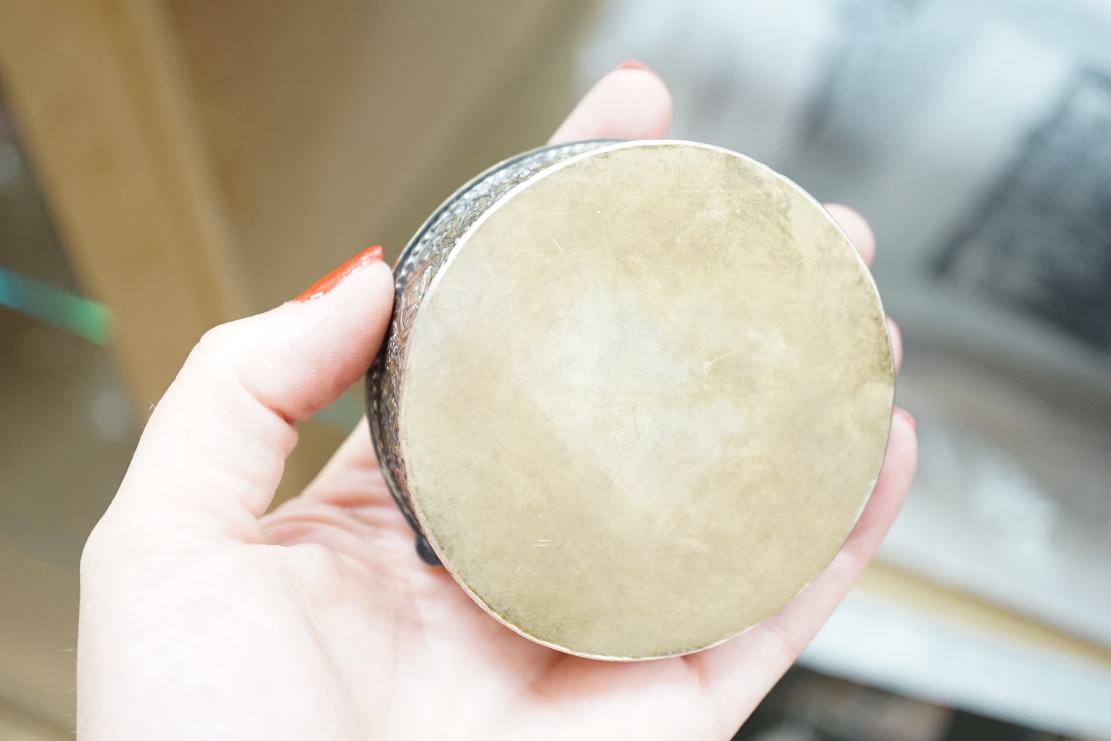 An Indian? embossed white metal circular box, with gilt and enamelled hinged cover decorated with Indian dancers, diameter 73mm.